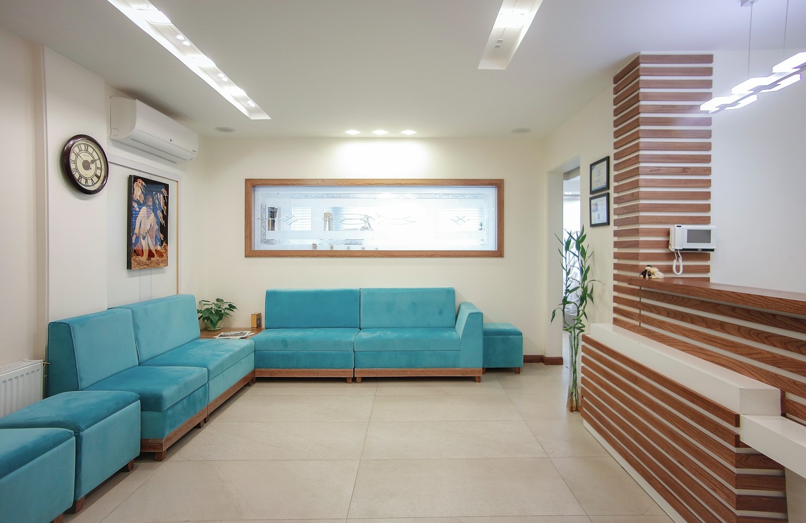 Einladender Wartebereich der Zahnarztpraxis mit blauem Sofa und Pflanze